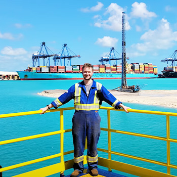 Captain Arran standing on the deck of a ship with the water in the background