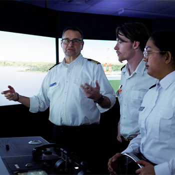 Michaela and another student with their instructor in the navigation simulator.