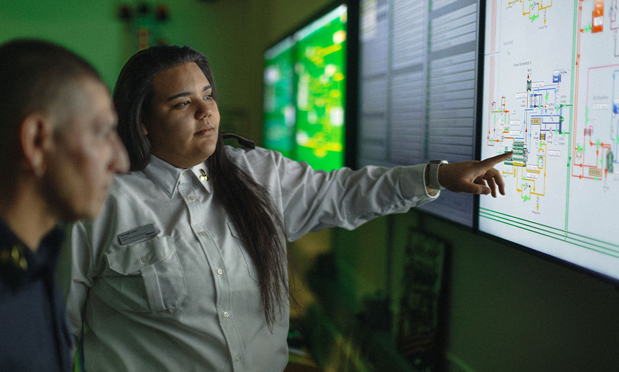 Two marine engineering students standing side by side, one pointing at a screen