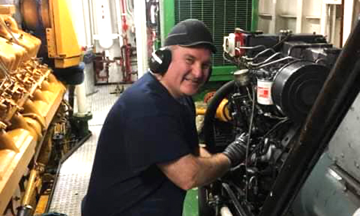 headshot of Charles Maclean repairing an ship engine.