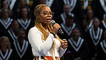 An African Canadian woman singing into a microphone during a Convocation ceremony.