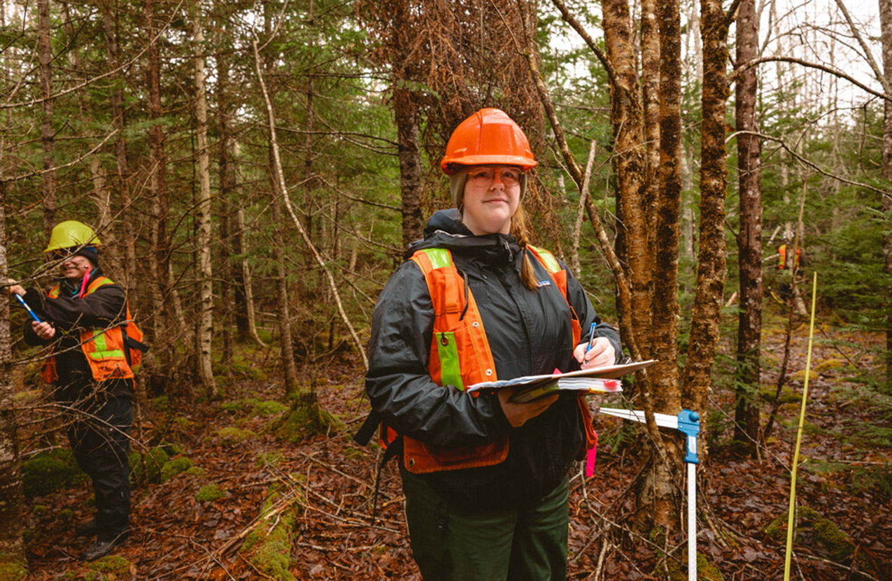 An NRET student taking notes in the forest