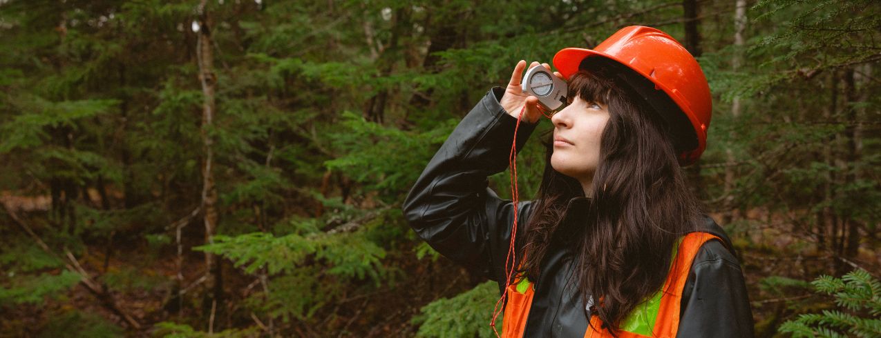 NSCC student wearing orange safety vest in the forest.