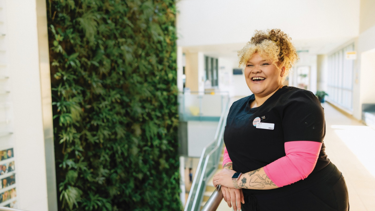 2025-26 NSCC Foundation and Alumni Relations Annual Report cover photo of NSCC alum, Reign, in black scrubs wearing NSCC trans pride pin.