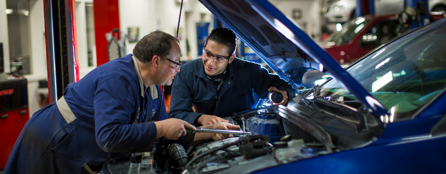 Photo of Syrian refugee student Fadi, working on vehicle with NSCC automotive faculty member.