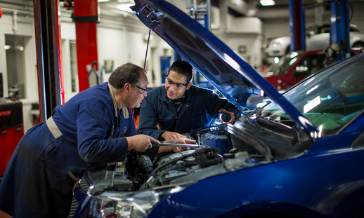 Photo of Syrian refugee student Fadi, working on vehicle with NSCC automotive faculty member.