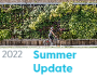 Summer 2022 Update link with photo of person on bike driving by green wall