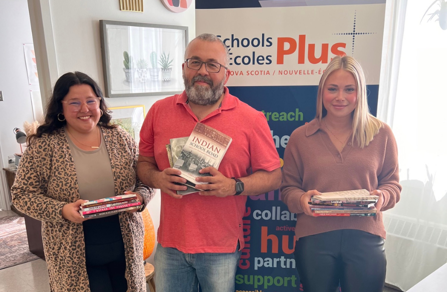 TCRCE SchoolsPlus staff holding some of the books they received in the Foundation's giveaway.