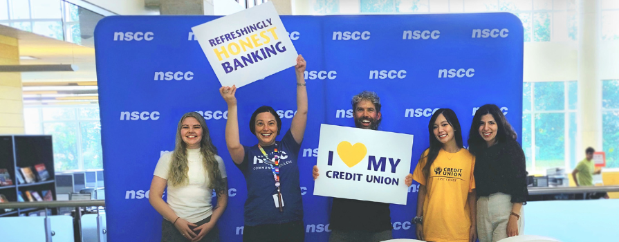 Photo of NSCC students and East Coast Credit Union staff in front of NSCC banner holding East Coast Credit Union promotional signs. 