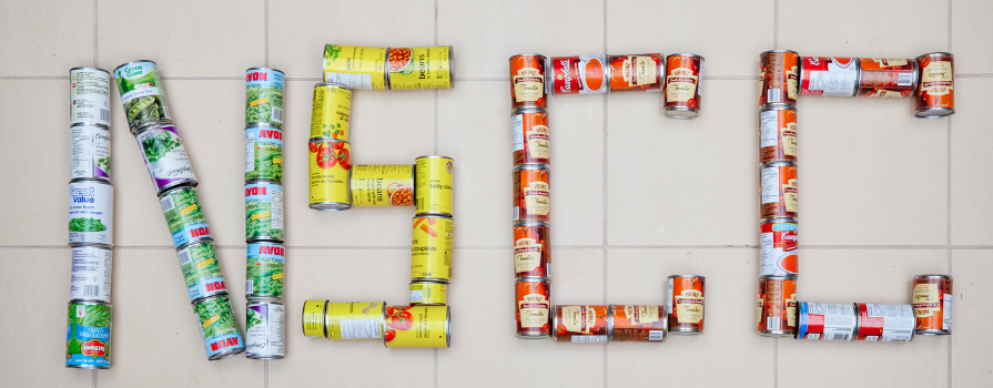 Photo of donated canned food spelling "NSCC".