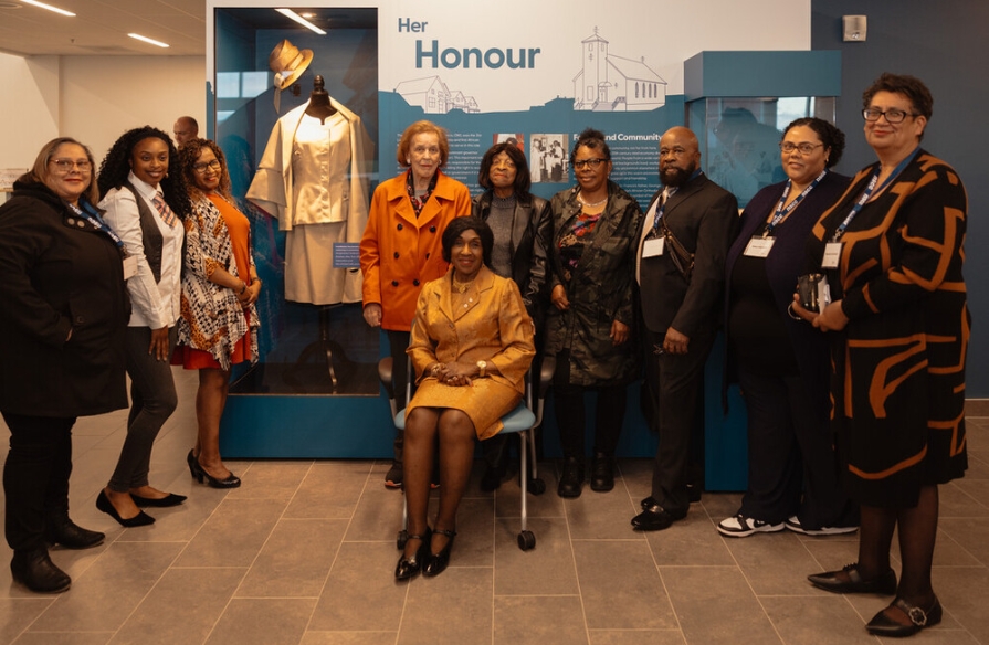 Group photo of The Honourable Dr. Mayann Francis with friends and family in front of her interpretative display at unveiling event.