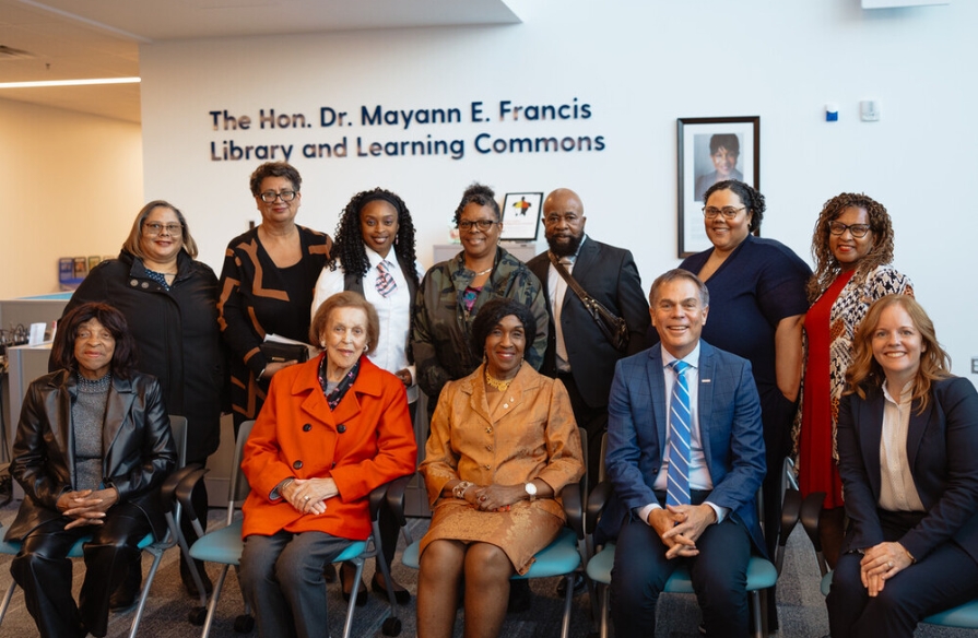 Group photo of The Honourable Dr. Mayann Francis with friends, family and NSCC's Carla Arsenault and Don Bureaux in front of named space at unveiling event.