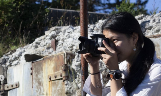 Photo of Amber H. taking a photo with her camera outside.