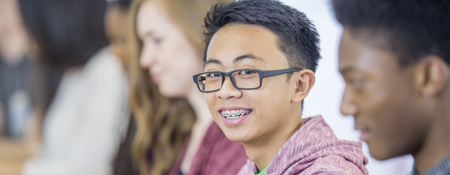 Young student sits in class smiling