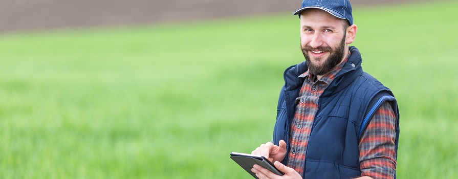 Man standing in field with a tablet computer