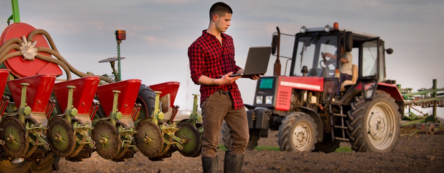 Farmer standing in a field with laptop computer