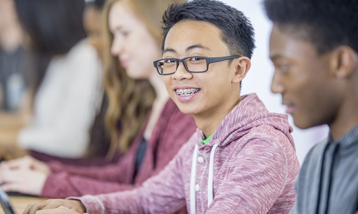 Male student sitting in a classroom and smiling