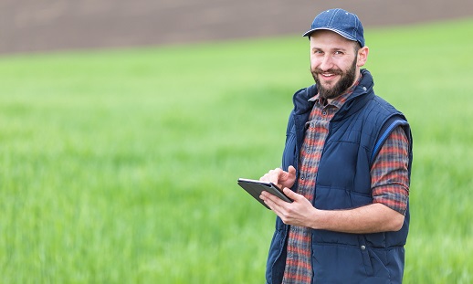 Man standing in a field with a tablet computer