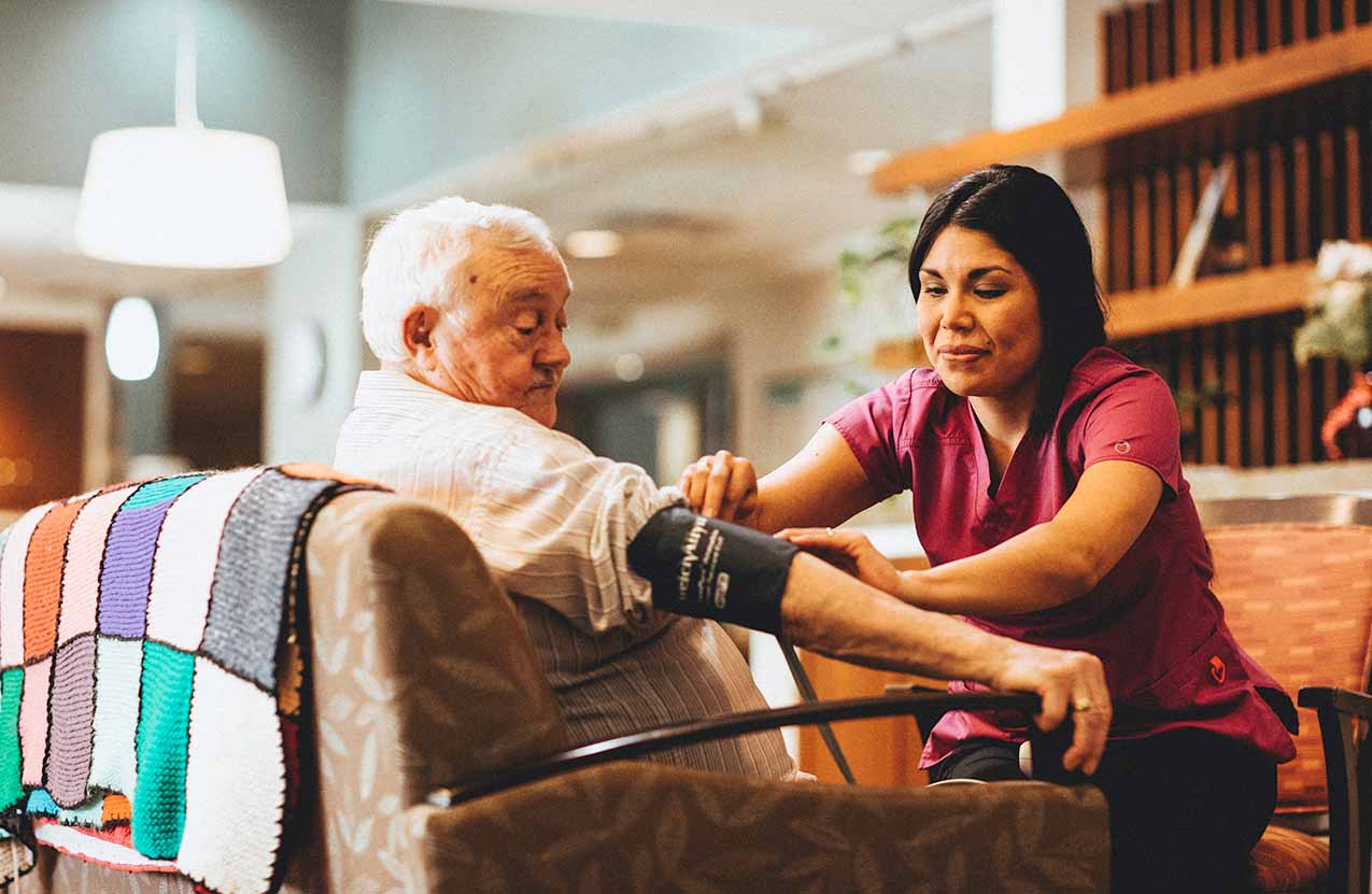 A student takes an elderly man's blood pressure.