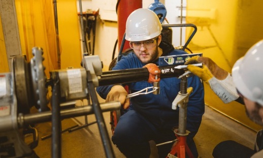 A person working on pipes in a training setting.