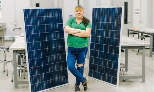 A person standing between solar panel in a classroom setting.