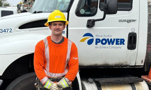 Student standing beside a Nova Scotia Power service vehicle during hands-on training.