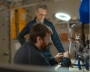 Two researchers examining electronics under a bright light in a lab. 
