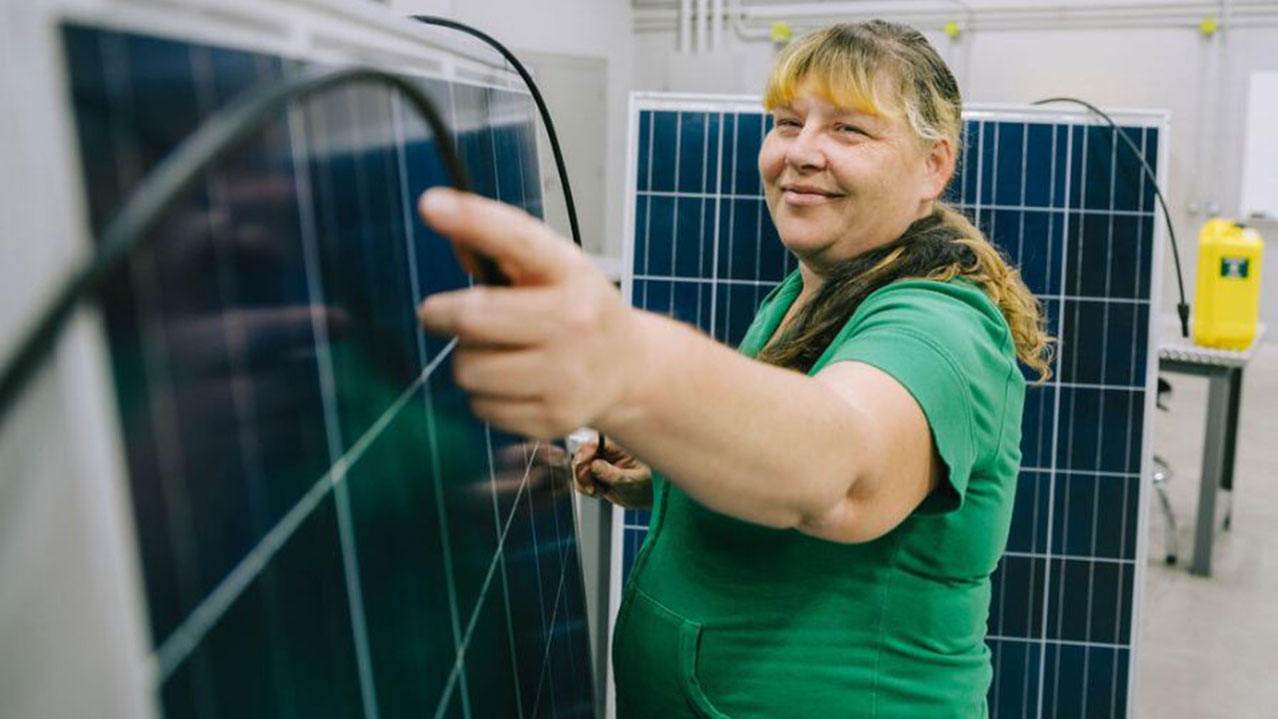 A person connected wires on a solar panel in a classroom.