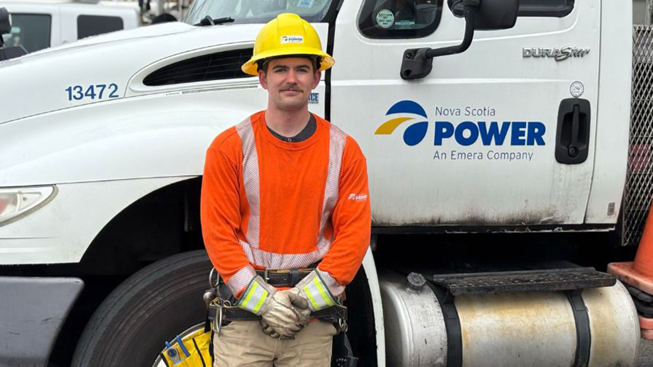 Student standing beside a Nova Scotia Power service vehicle during hands-on training.