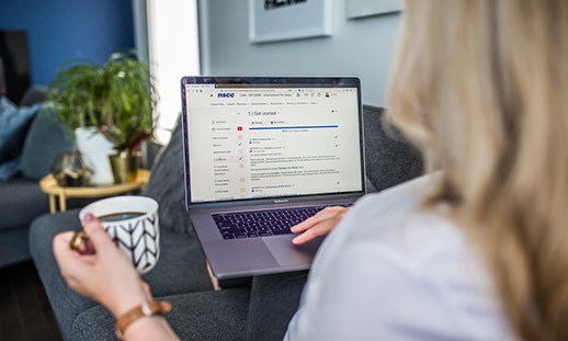 Image of a laptop sitting on a woman's lap in a livingroom