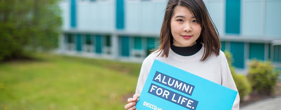 Young woman holding an NSCC alumni for life sign. for life