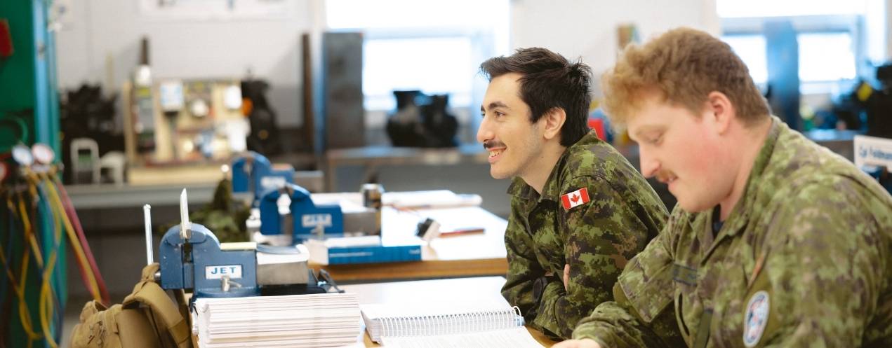 Two people in uniform learning in a classroom.