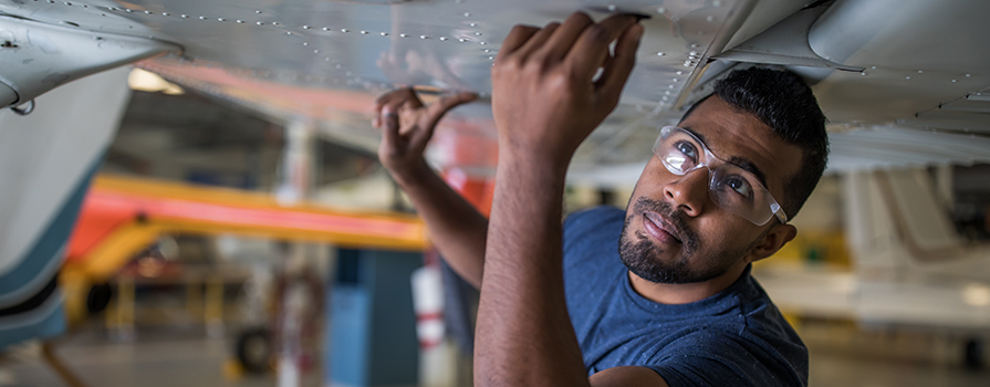A student examines the wing of a small airplane.
