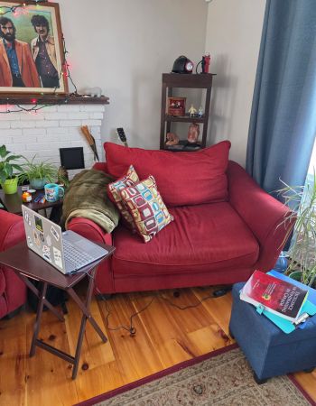 Lynn's study area in her home features a comfy red chair and a table with a laptop on it.
