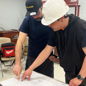 Reese with his instructor Flavio looking at blueprints together