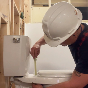 Reese installing a toilet fixture as part of his Plumbing program.