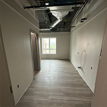 Pictured is an apartment room under construction with fresh drywall.