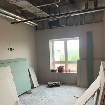 A construction site shows a freshly built room with drywall installed.
