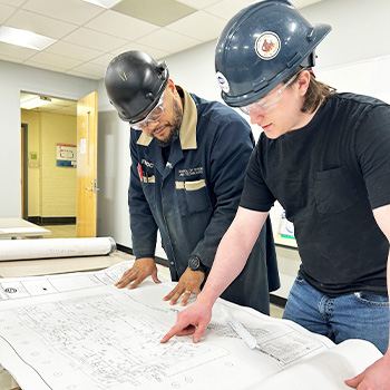 Austin and his instructor looking at a set of blueprints