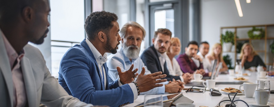 A group of employees sitting around a conference room table in a meeting.