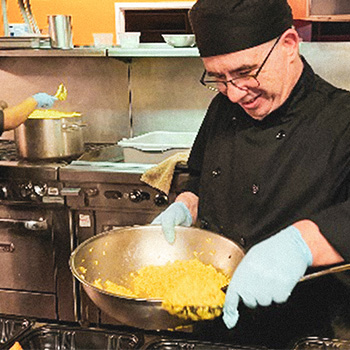 Employee stirring eggs in a bowl while in a kitchen