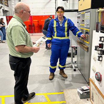 Chelsea King, Marine Navigation Technology student speaks with a judge while participating in a contest in the engine shop