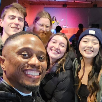 A group of students gather together for a photo in their classroom.