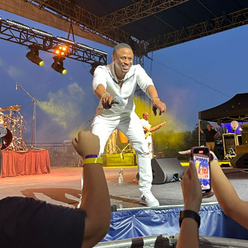 A person is performing on stage, holding a microphone and pointing out to the audience.