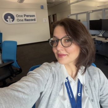 Image of a woman in an office setting taking a selfie.