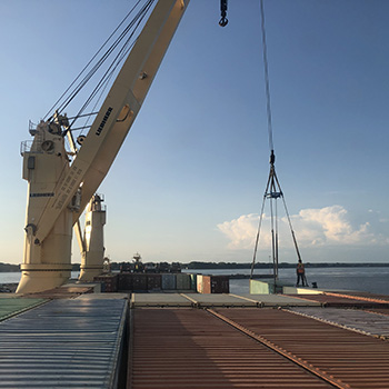 A crane and shipping containers aboard a ship.