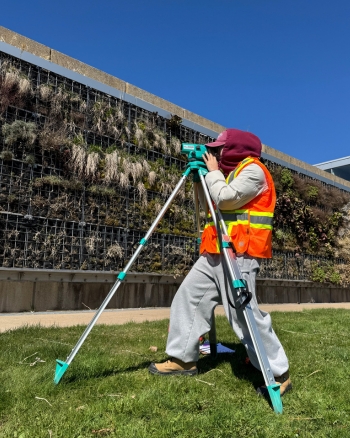An NSCC student uses surveying equipment outside Ivany Campus.
