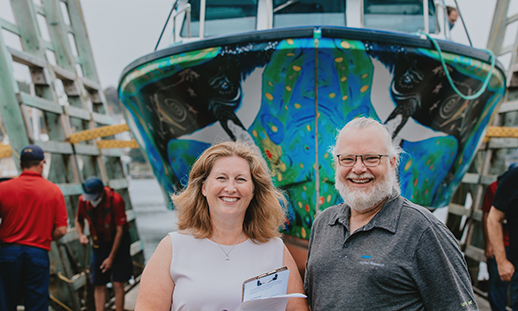 Man and woman standing in front of an electric boat.