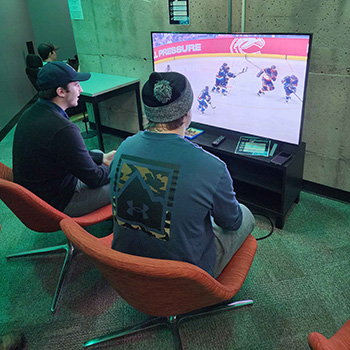Two students sitting in the Esports Lounge playing a game.