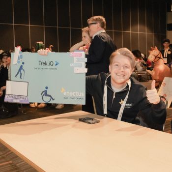 NSCC grad Avery Cote is shown holding a sign promoting his app, Trek.IQ, at an Enactus Canada event.